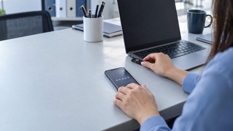 Biztonsági kulcsot csatlakoztató kéz laptop mellett